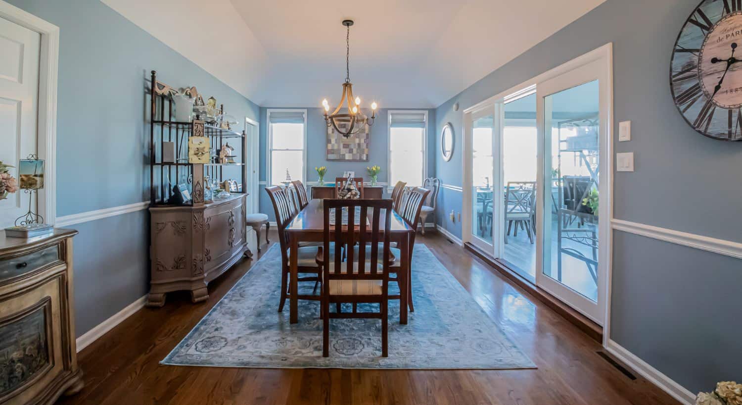 Dining room with light blue walls, hardwood flooring, wood table and chairs, and view into game room