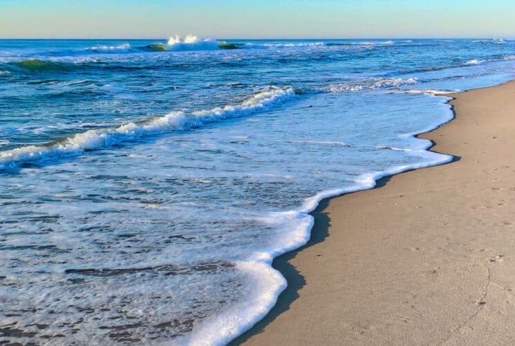 Light waves rolling on to white sandy beach