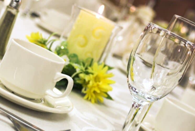 Close up view of a formal dining table with tablecloth, place settings, and yellow candle