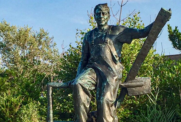 Statue representing area fishermen with green shrubs in the background