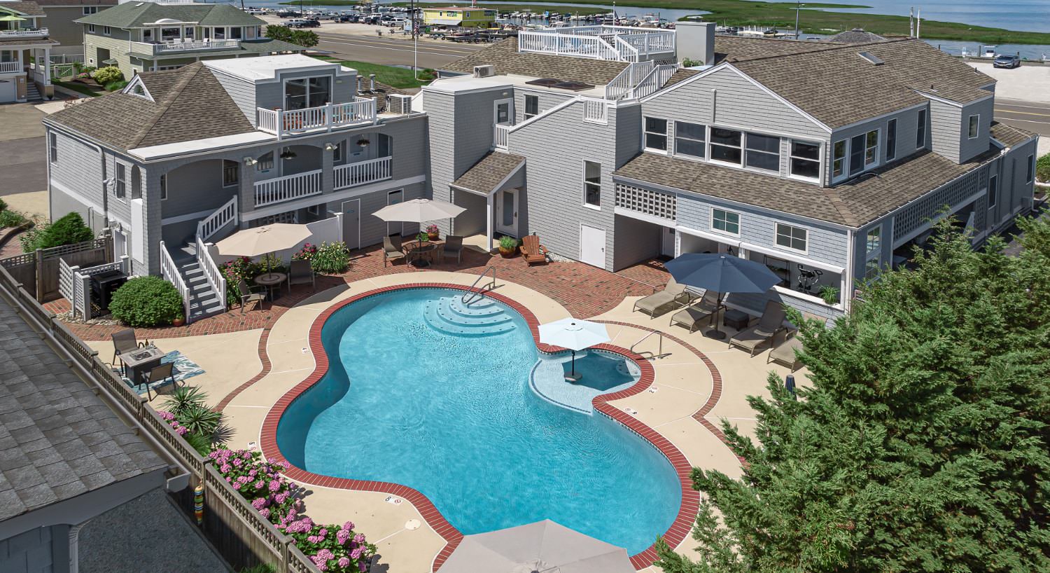 Exterior view of the property with light gray shake siding, patio with patio furniture, and pool