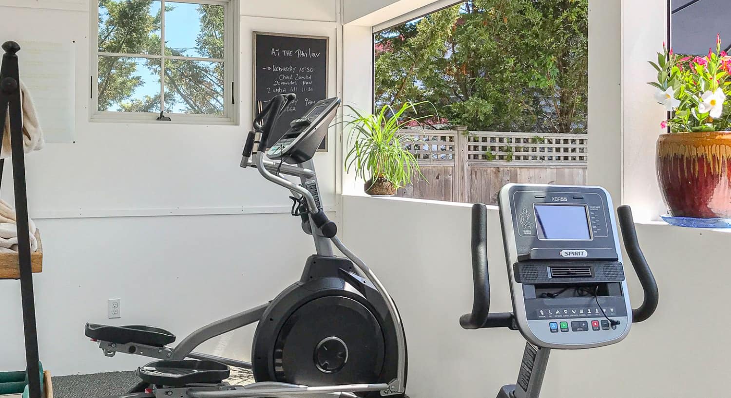 Workout room with exercise equipment and open windows to the backyard pool