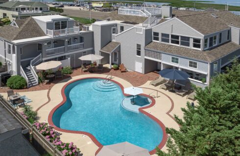 Exterior view of the property with light gray shake siding, patio with patio furniture, and pool