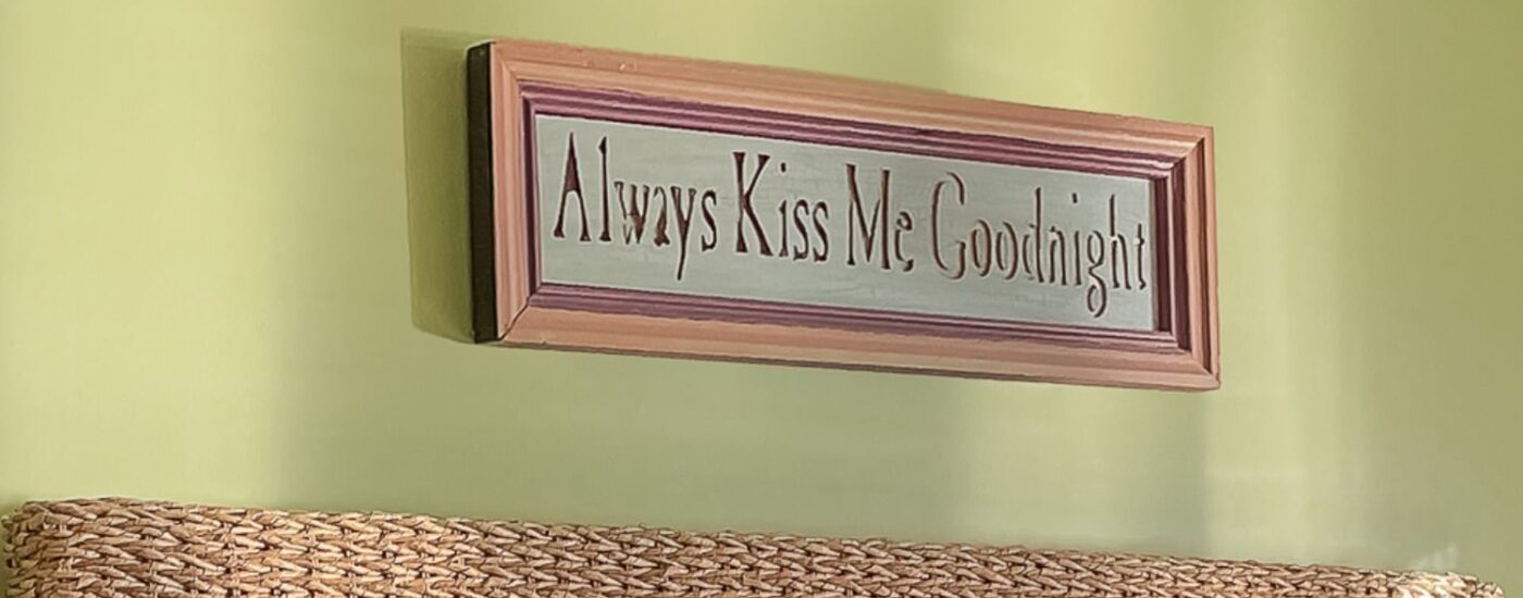 Close up view of framed picture saying Always Kiss Me Goodnight hanging on lime green wall