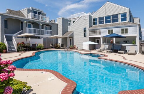 Exterior view of the property with light gray shake siding, patio with patio furniture, and pool