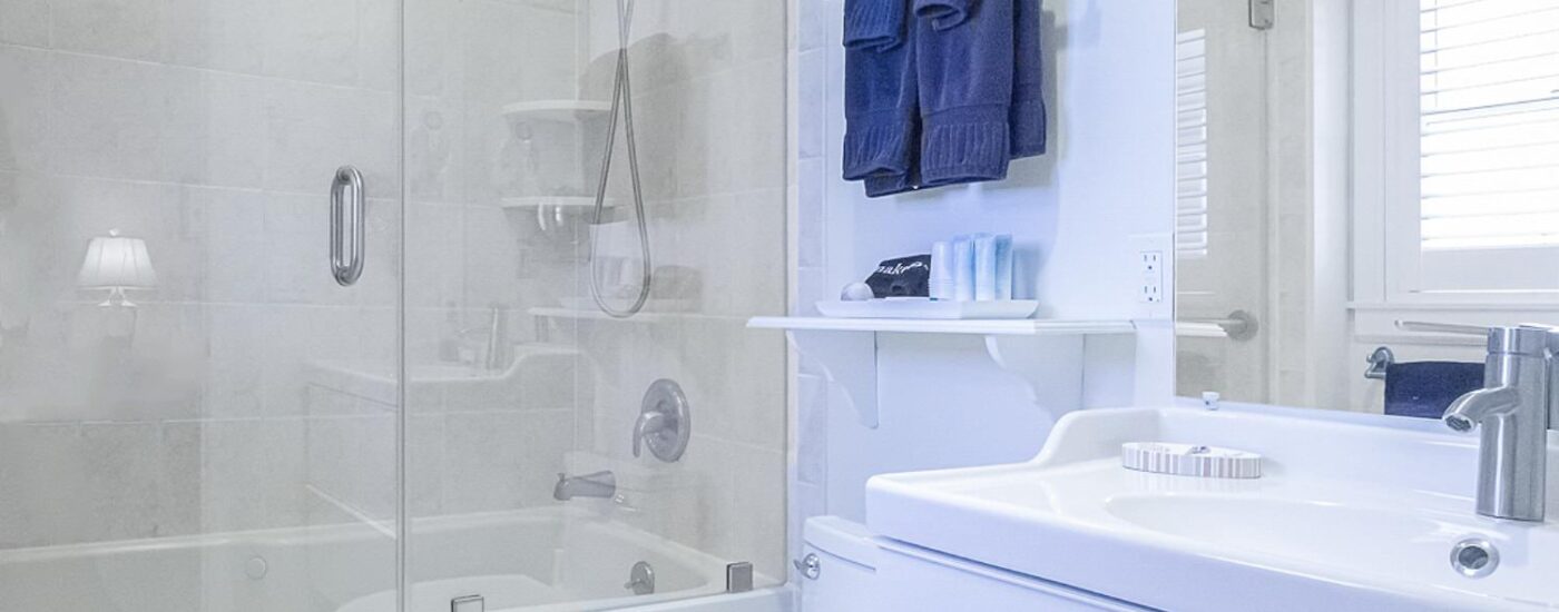 Bathroom with light blue walls, shower/tub combo, white vanity, and white countertop