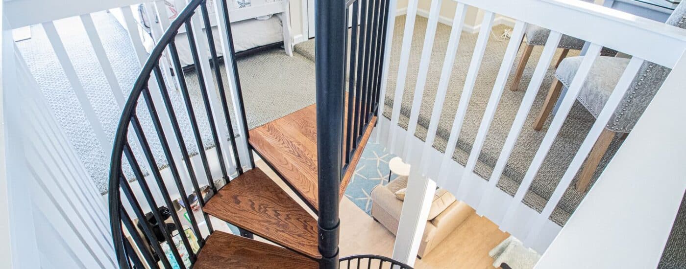 Bedroom suite's spiral staircase with wooden stairs and black wrought iron railing
