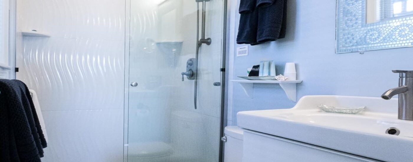 Bathroom with light blue walls, walk in shower, white vanity, and white countertop