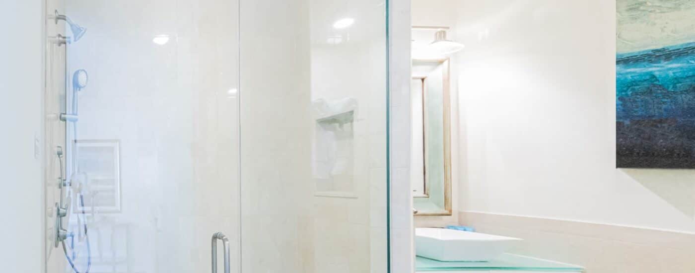 Bathroom with light walls, walk in tiled shower, white vanity, and light blue countertop