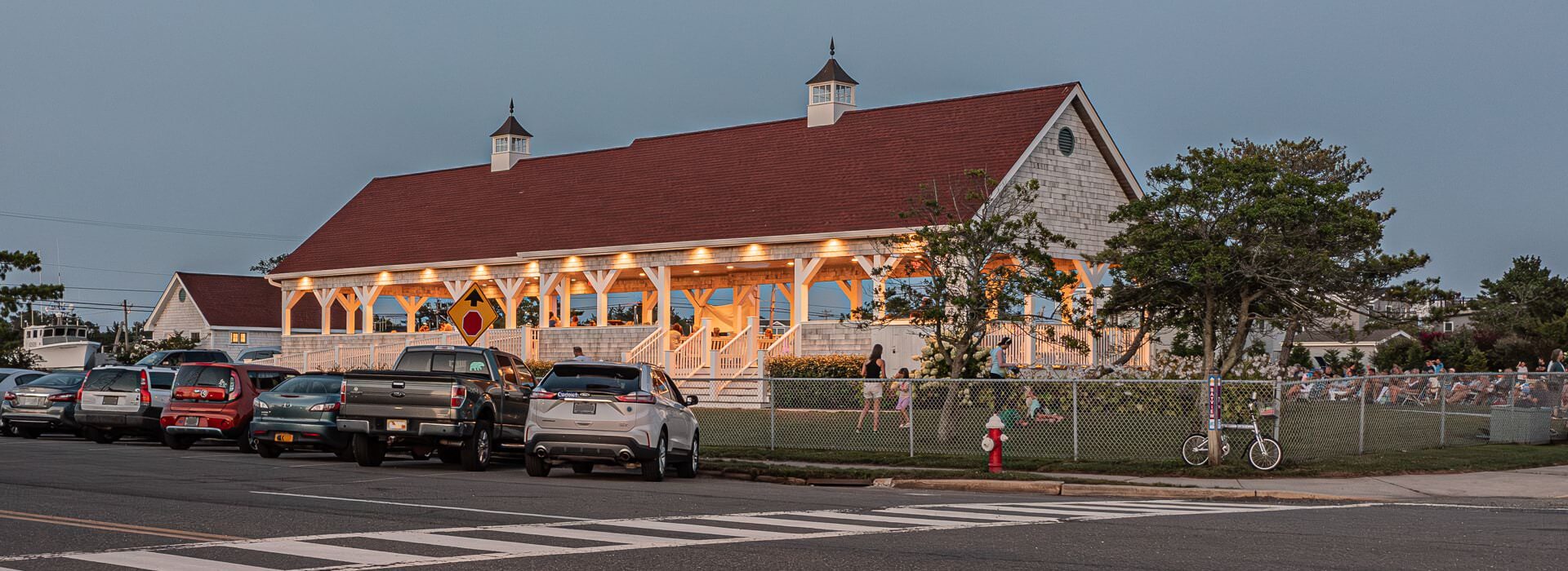 Outdoor wooden pavilion used for community events surrounded by green grass, green shrubs, and green trees