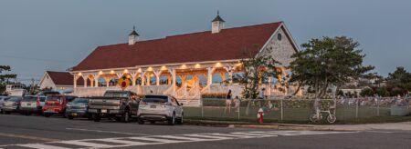 Outdoor wooden pavilion used for community events surrounded by green grass, green shrubs, and green trees