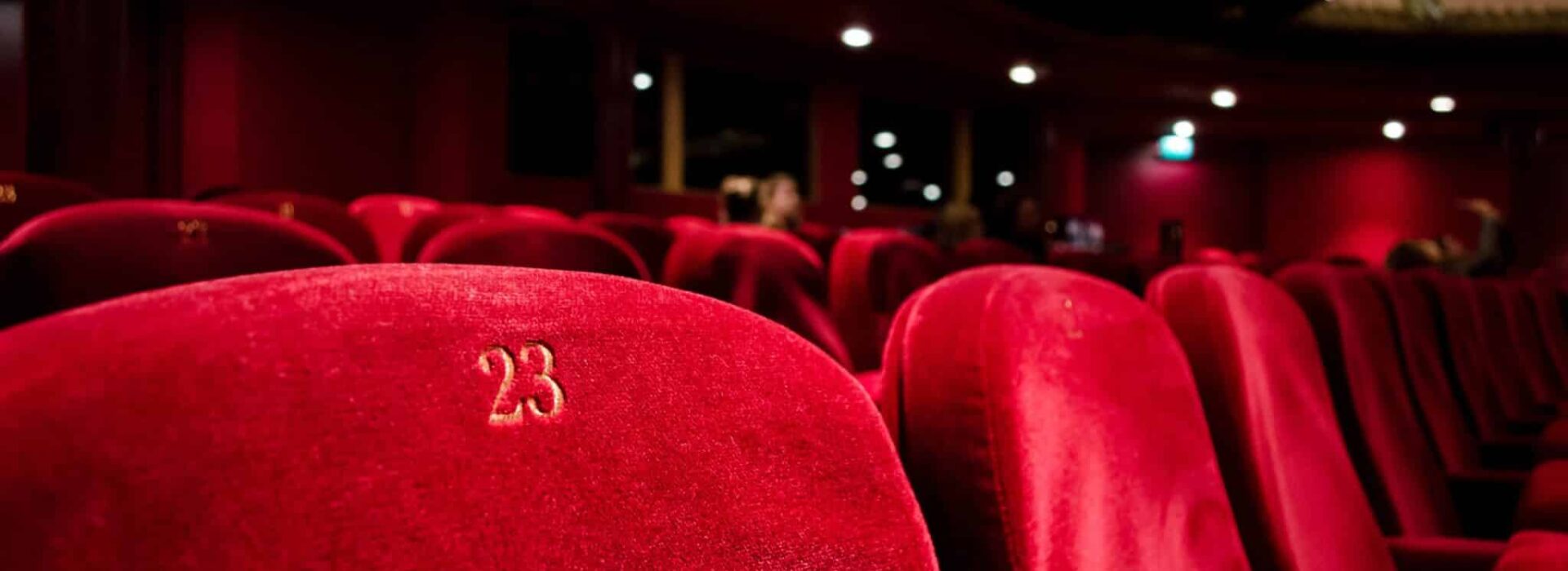 Rows of red velvet seats in a dark theatre