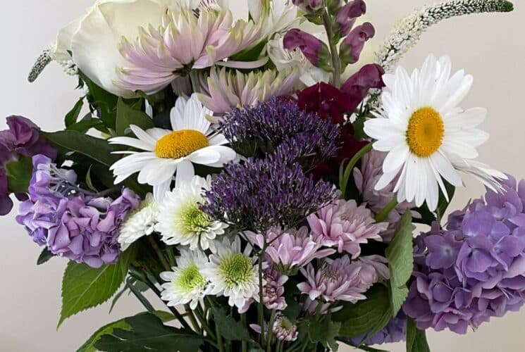 Close up view of white, lavender, and purple flowers in a glass vase