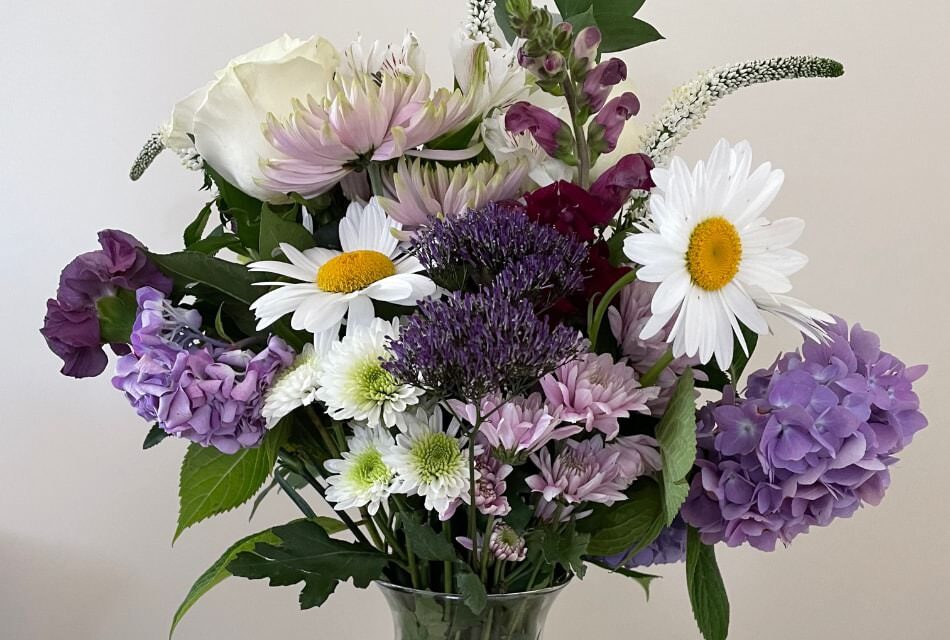 Close up view of white, lavender, and purple flowers in a glass vase