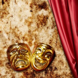 Gold theater masks next to a red curtain